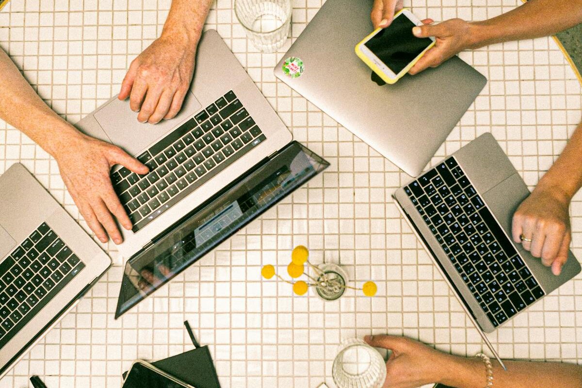 Team collaborating with laptops and phones in a modern office - Photo by Canva Studio