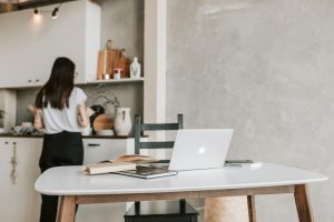 Woman Standing Near The Kitchen Counter With Her Laptop Open On Table