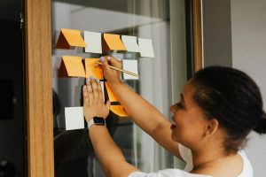 Woman Writing on Sticky Note on Window