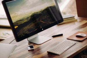 space gray iMac near Magic Keyboard on brown wooden computer desk during daytime